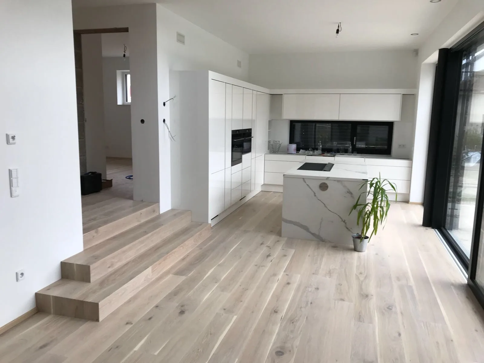 Heller Holzfußboden mit verkleideten Stufen in einer Küche